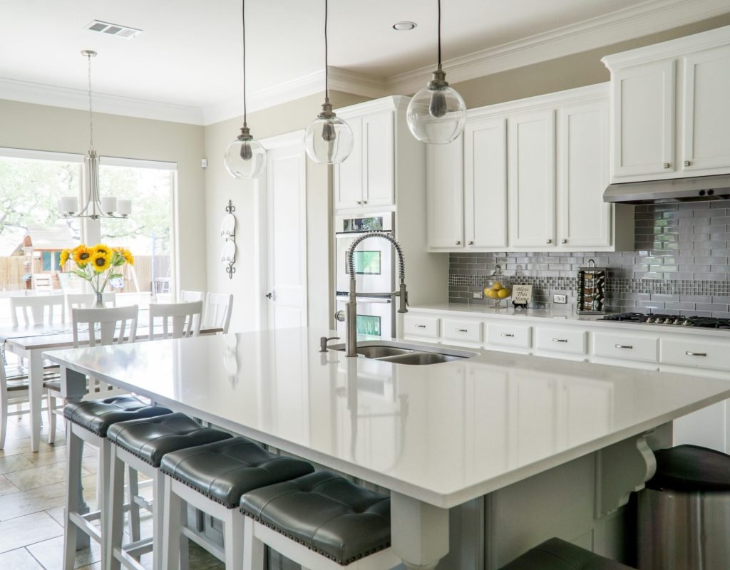 Spacious modern kitchen with white cabinets and island in natural light.